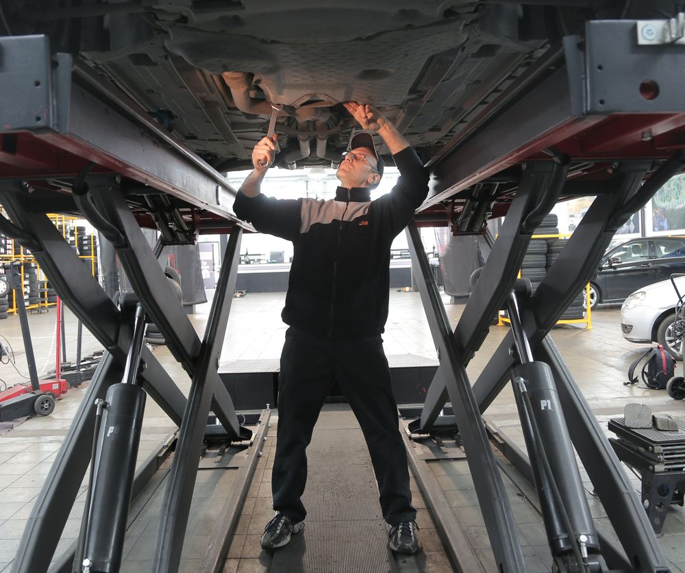 Illustrative stock photograph of a mechanic inspecting the underside of a raised vehicle
